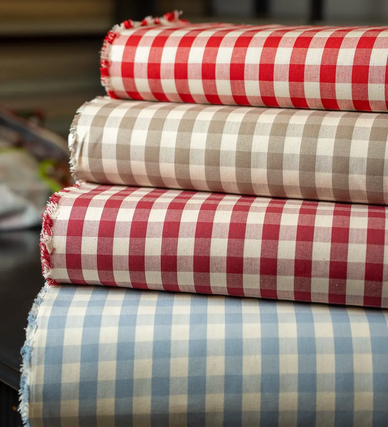 Pezze di cotone a quadretti rossi, beige e azzurri sul banco del negozio